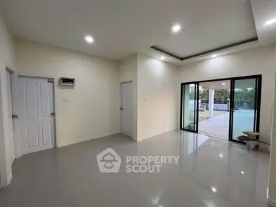 Spacious modern living room with large sliding glass doors and glossy tile flooring.