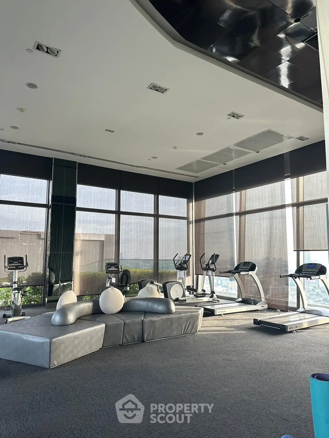 Modern gym with treadmills and exercise equipment in a high-rise building with city views.