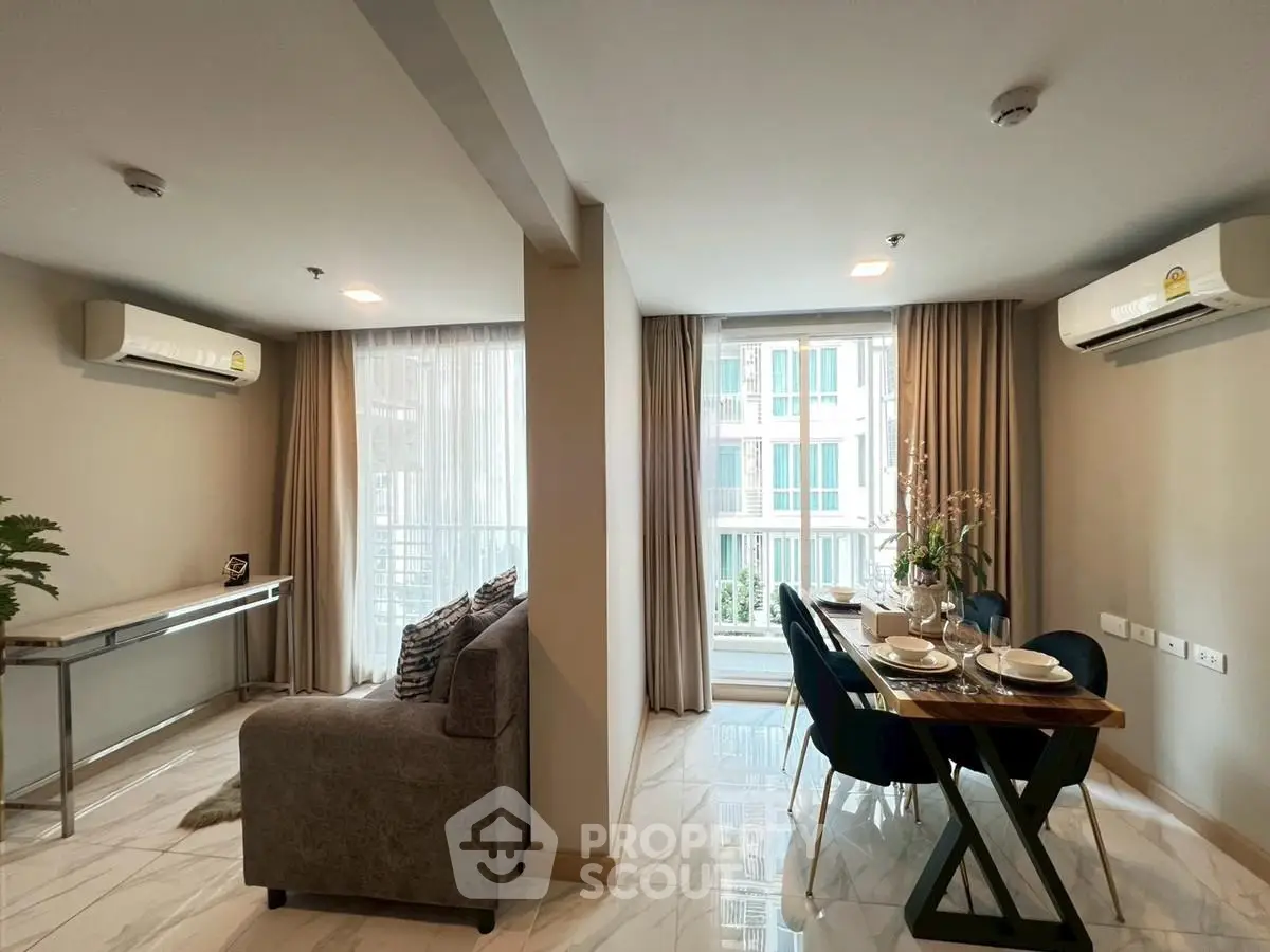 Modern living and dining area with large windows and air conditioning in a stylish apartment.