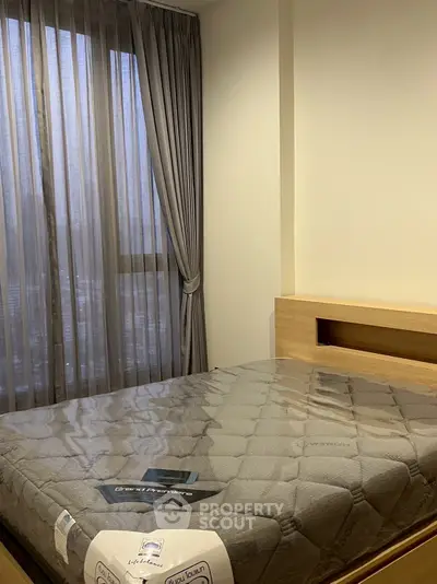 Cozy bedroom with large window and elegant curtains, featuring a modern bed setup.