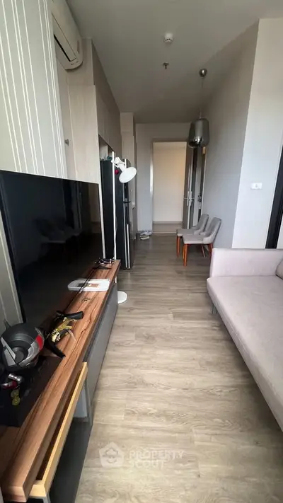 Modern living room with sleek furniture and wooden flooring, featuring a flat-screen TV and stylish decor.