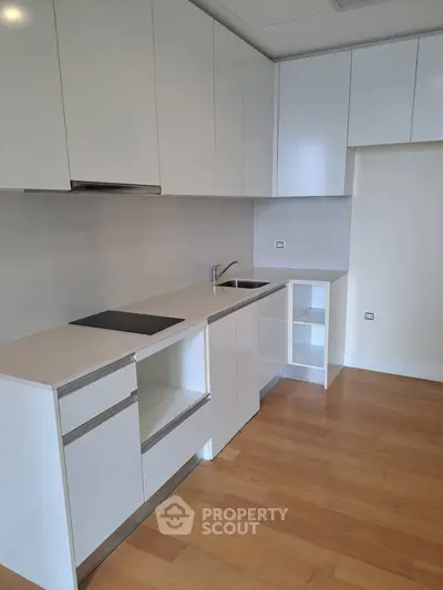 Modern minimalist kitchen with sleek white cabinets and wooden flooring