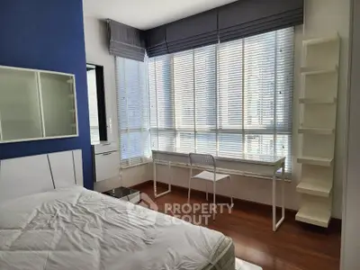 Modern bedroom with large windows and stylish furnishings in a high-rise apartment.