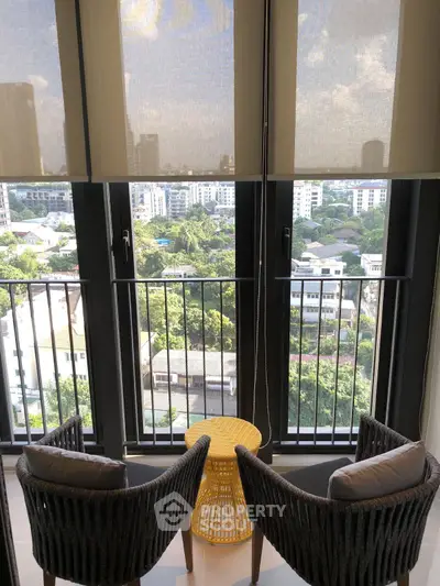 Chic urban balcony with stunning cityscape view and cozy seating area.