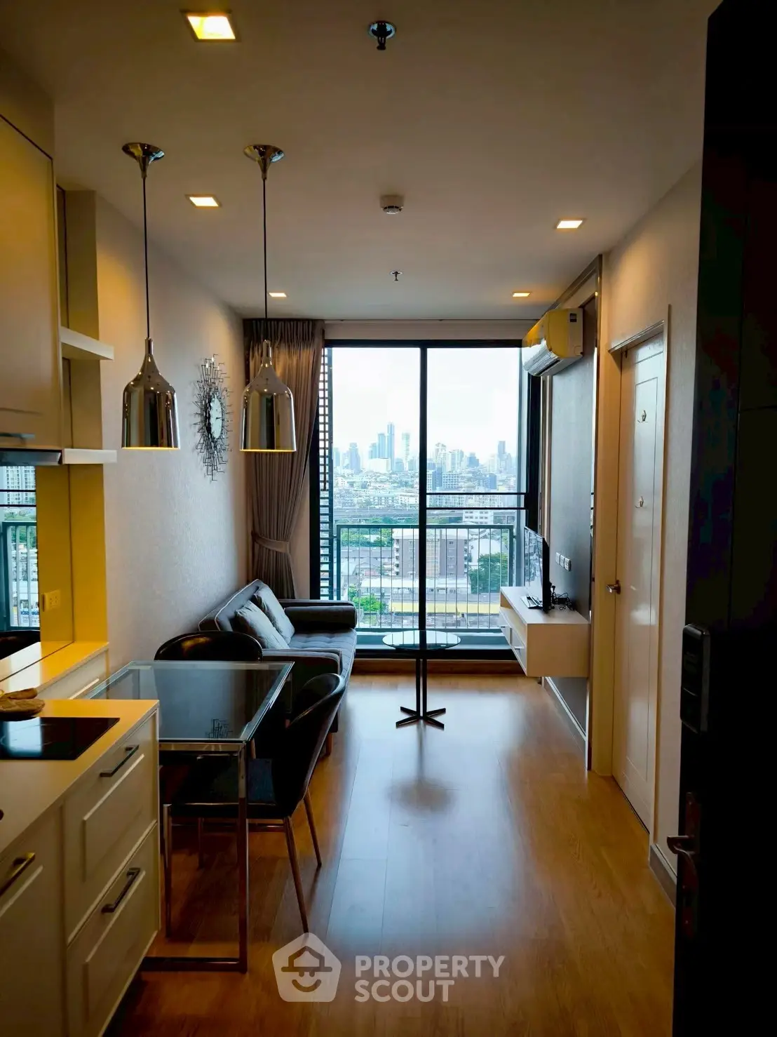 Modern living room with city view and open kitchen layout in high-rise apartment.