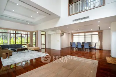 Spacious open-plan living and dining area with elegant hardwood floors and large windows.