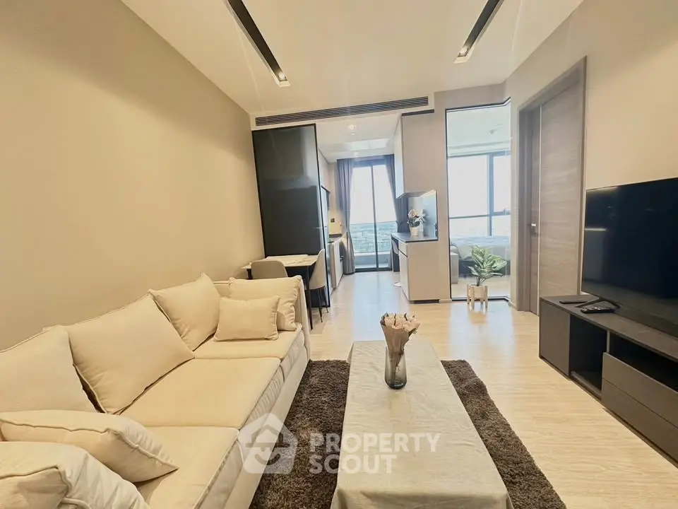 Modern living room with cozy beige sofa and open kitchen layout, featuring a stunning view from the balcony.