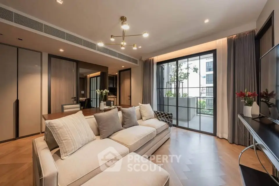 Spacious modern living room with elegant decor and large windows opening to a balcony.