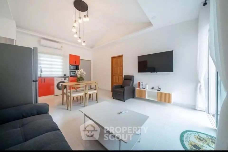 Modern living room with open kitchen, sleek furniture, and bright lighting
