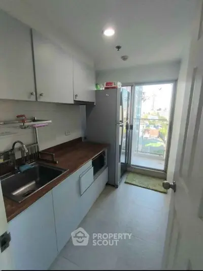 Modern kitchen with sleek cabinetry and balcony view, featuring stainless steel appliances and ample natural light.