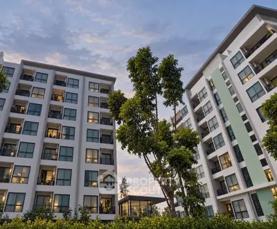 Modern apartment buildings with lush greenery and evening sky view.
