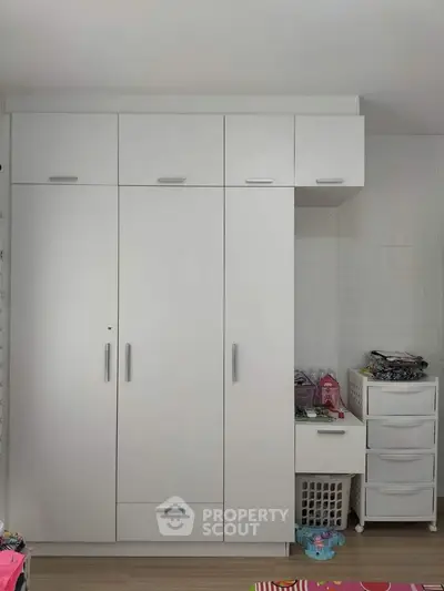 Spacious white wardrobe with ample storage in modern bedroom setting.