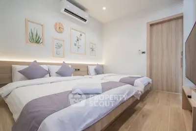 Modern bedroom with twin beds, stylish decor, and wooden flooring in a cozy apartment.