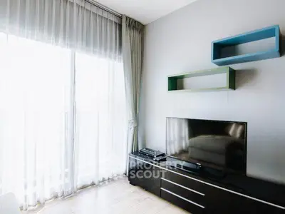 Modern living room with large TV and stylish shelving, featuring floor-to-ceiling windows and elegant curtains.