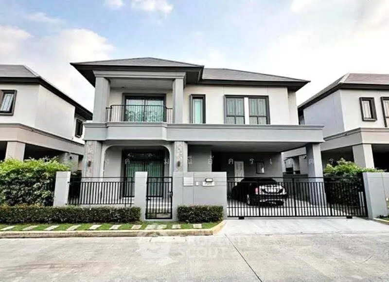 Modern two-story house with gated driveway and landscaped front yard in a suburban neighborhood.