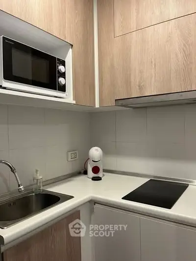 Modern compact kitchen with microwave and electric stove in sleek design.