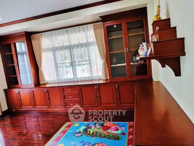 Elegant wooden cabinetry in a spacious living room with colorful rug and natural light.