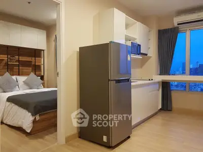 Modern apartment interior with kitchen and bedroom view, featuring sleek appliances and cityscape window.