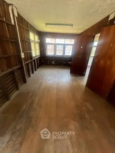 Spacious wooden interior room with large windows and natural light, ideal for renovation or creative use.