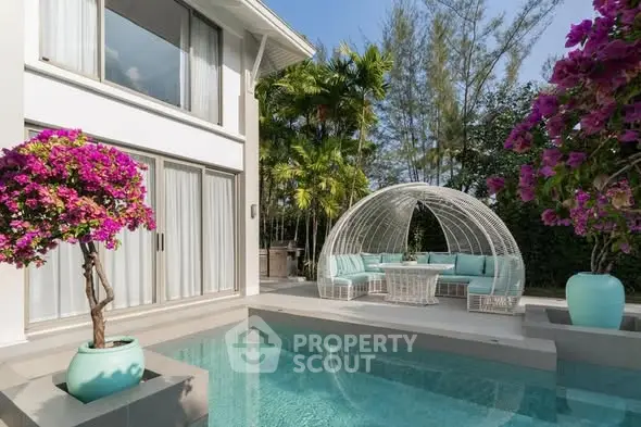Luxurious modern villa with private pool and stylish outdoor seating area, surrounded by lush greenery and vibrant flowers.