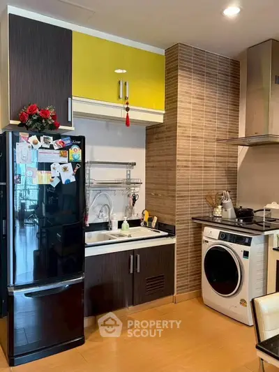 Modern kitchen with sleek appliances and stylish cabinetry in a cozy apartment setting.