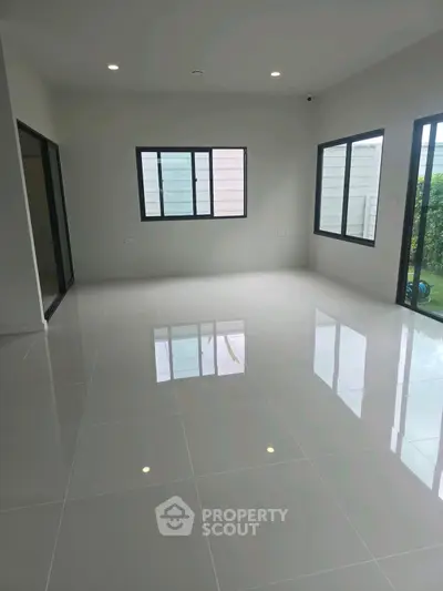 Spacious modern living room with glossy tiled floor and large windows.