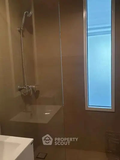 Modern bathroom with sleek shower and frosted window for privacy.