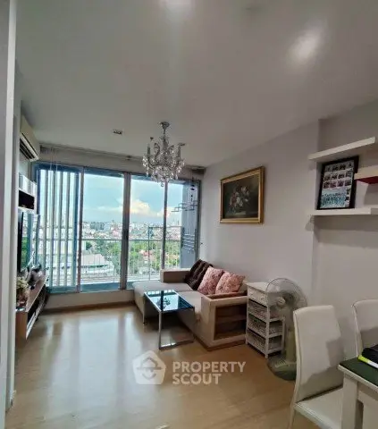 Modern living room with city view, elegant chandelier, and cozy seating area.