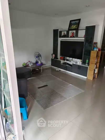 Spacious living room with modern entertainment center and sleek tile flooring.