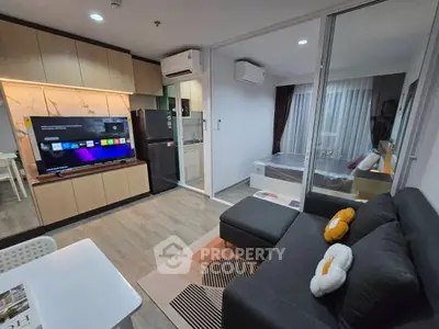 Modern open-plan living room with sleek kitchen and cozy bedroom view.