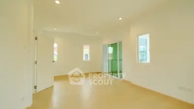 Spacious empty room with wooden flooring and large windows in modern home