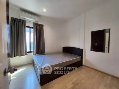Cozy bedroom with natural light, featuring a bed and wooden flooring, perfect for restful nights.