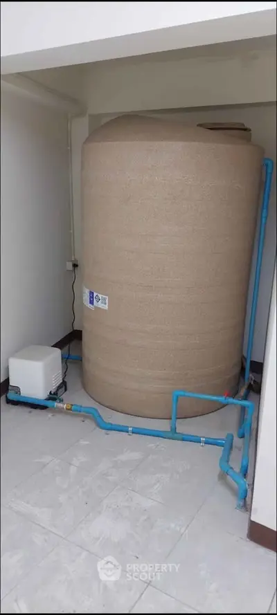 Spacious utility area featuring a large water tank with connected plumbing, ideal for efficient water management.