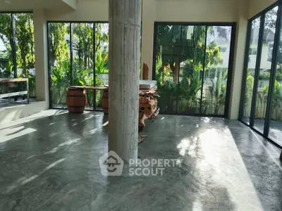 Spacious living area with large windows and lush garden views, perfect for relaxation and entertaining.