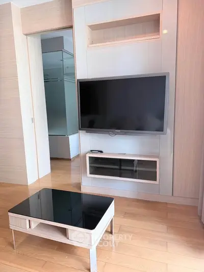Modern living room with sleek TV setup and stylish coffee table on wooden flooring.