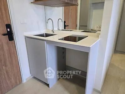 Modern compact kitchen with sleek design and induction cooktop in a stylish apartment.
