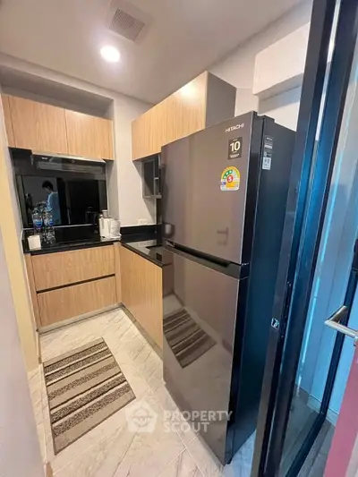 Modern kitchen with sleek black fridge and wooden cabinets in compact layout