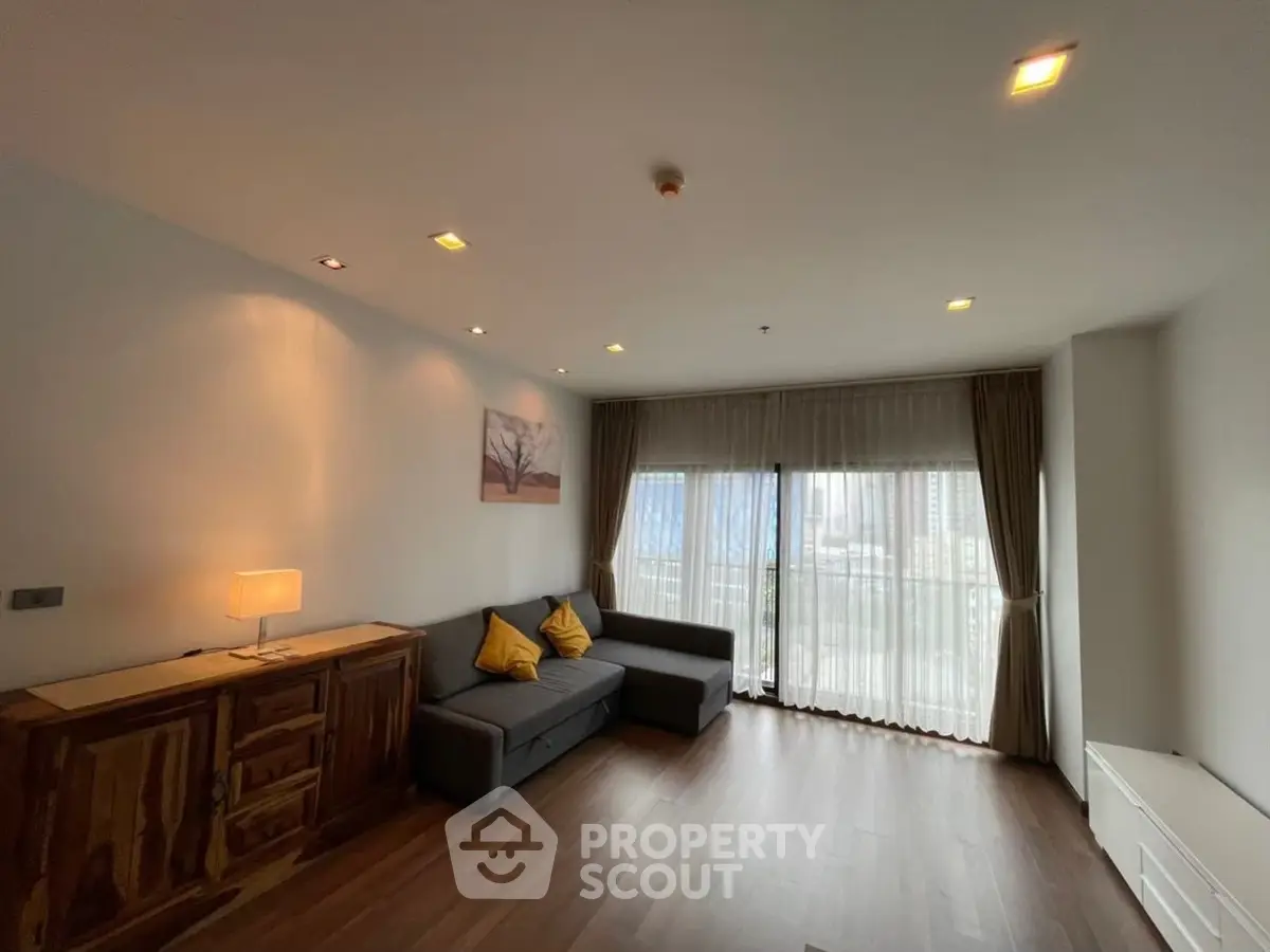 Spacious living room with modern decor and large windows offering city views.