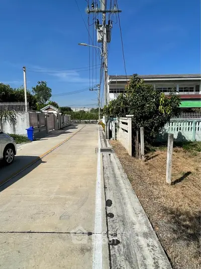 Quiet residential street with clear blue sky, showcasing suburban living and potential property opportunities.