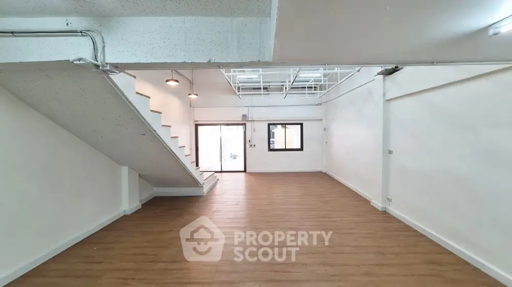 Spacious multi-level open floor plan interior with hardwood floors, industrial-style ceiling, and ample natural light from large windows, ideal for creative loft living.