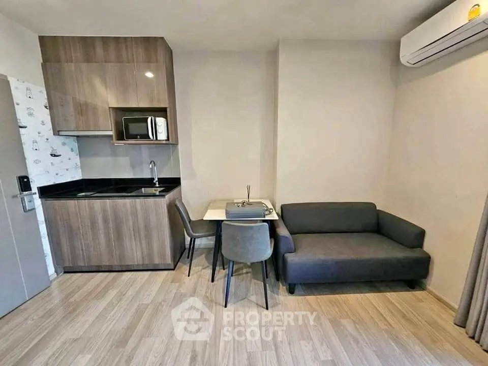 Modern compact kitchen and living area with sleek design and cozy seating.