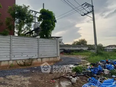 Vacant land with potential for development, featuring utility access and partial fencing.