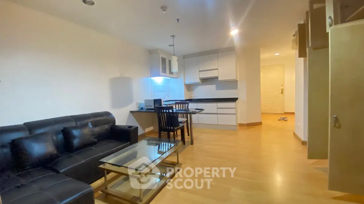 Modern open-layout living room and kitchen with sleek furniture and wooden flooring.