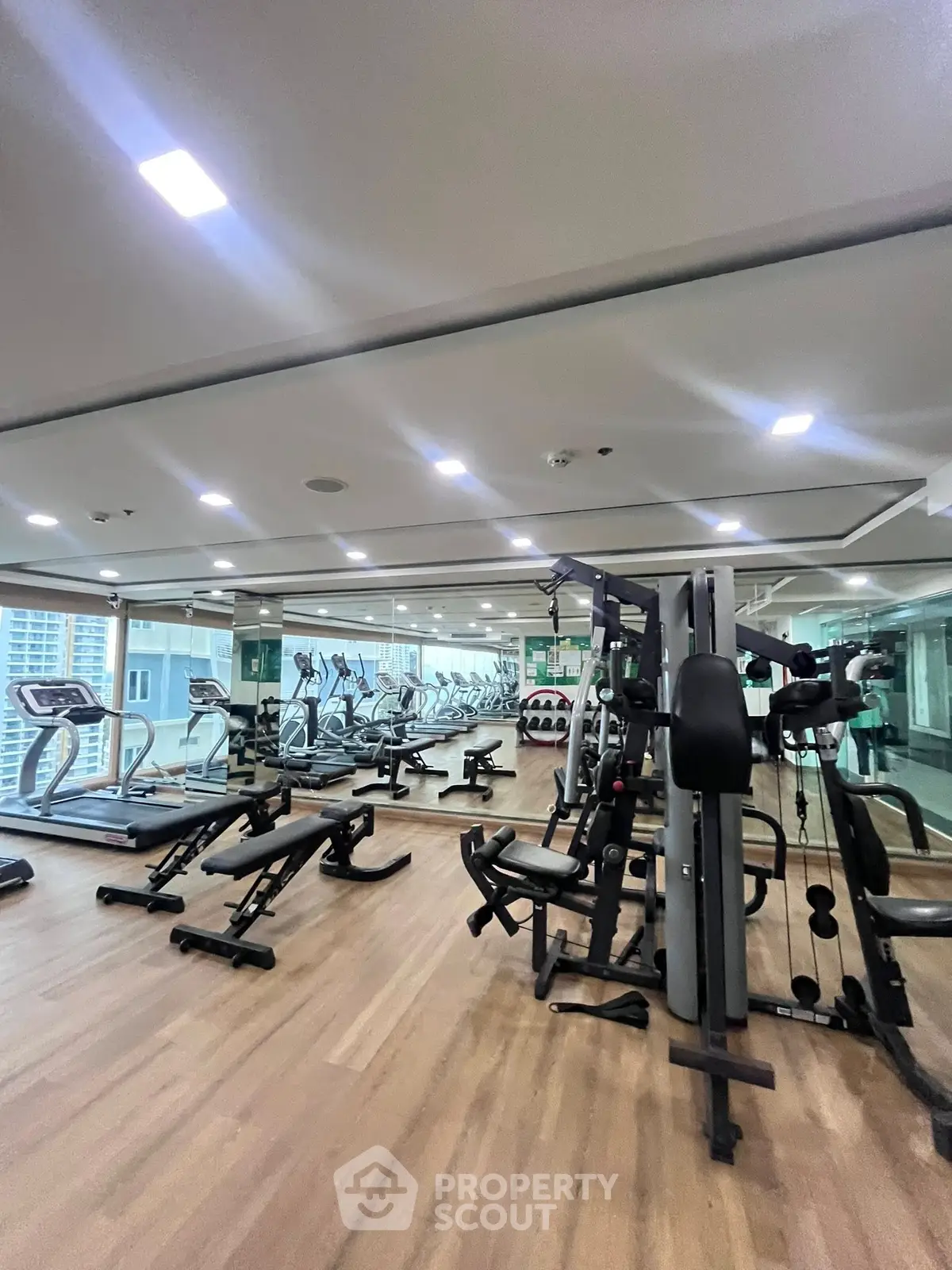 Spacious modern gym with state-of-the-art equipment and mirrored walls in luxury building.