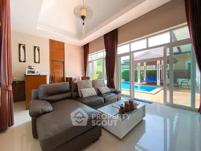Luxurious living room with pool view, featuring modern leather sofa and elegant decor in a spacious open layout.