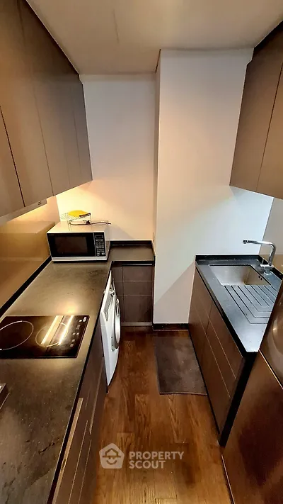 Modern kitchen with sleek dark cabinetry and built-in appliances, featuring a compact and efficient layout.
