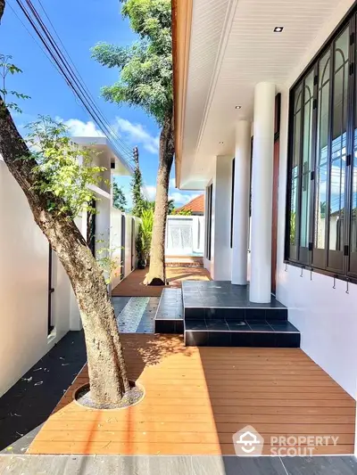 Modern exterior with wooden deck and sleek design featuring trees and natural light.