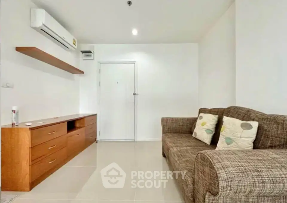 Modern living room with cozy sofa and sleek wooden cabinet under air conditioning.