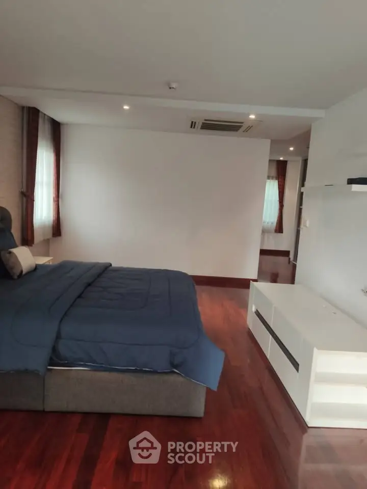 Spacious bedroom with elegant wooden flooring and modern furnishings