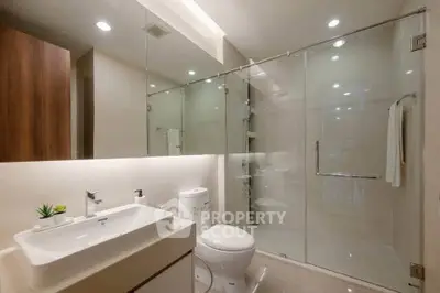 Modern bathroom with glass shower and sleek fixtures in contemporary apartment.